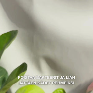 Lähikuva käsistä, jotka pumppaavat kädelle kirkasta, vaahtoavaa vaaleansinistä nestesaippuaa, jossa on teepuuöljyä, ja vaahdottavat sitä lempeästi kämmeniin, kämmenselkiin ja sormien väleihin — kerrostuva, puhdistava vaahto poistaa bakteereja ja epäpuhtauksia ja tekee ihosta pehmeän ja kosteutetun.