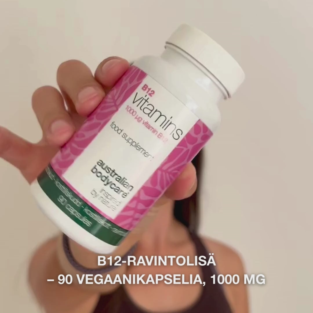 Lähikuva kädestä, joka pitää Vitamin B12 ravintolisäpulloa, avaa kannen ja kaataa ulos sileitä valkoisia kapseleita – tuote esitetään päivittäiseen käyttöön energian, immuunijärjestelmän ja hermoston tueksi sekä väsymyksen vähentämiseen.