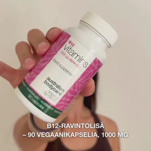 Lähikuva kädestä, joka pitää Vitamin B12 ravintolisäpulloa, avaa kannen ja kaataa ulos sileitä valkoisia kapseleita – tuote esitetään päivittäiseen käyttöön energian, immuunijärjestelmän ja hermoston tueksi sekä väsymyksen vähentämiseen.
