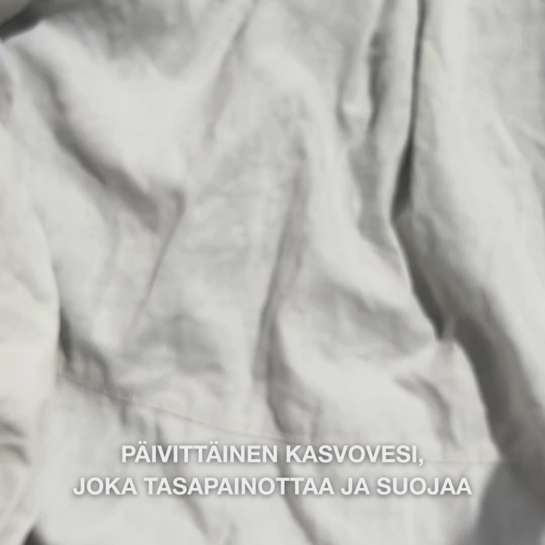 Lähikuva kädestä, joka tipauttaa muutaman pisaran kirkasta, vesimäistä Face Tonicia teepuuöljyllä pumpulille ja pyyhkii sitä hellästi puhtaalle kasvojen iholle: kevyt, raikas neste rauhoittaa, puhdistaa syvältä, kosteuttaa ja jättää ihon uudistuneeksi ja valmiiksi kosteusvoiteelle.