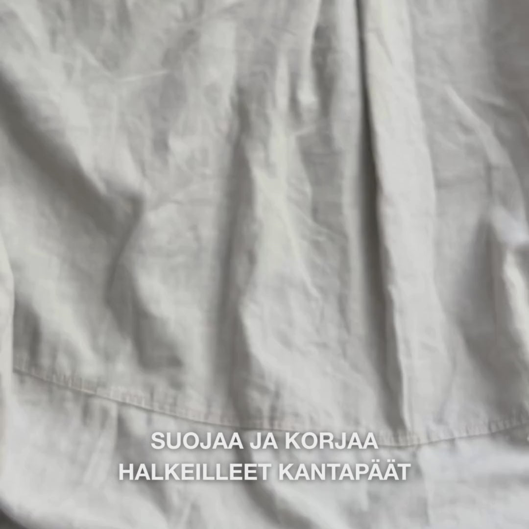 Lähikuva kädestä, joka ottaa rikasta, kermaista Heel Repair -voidetta kämmenelle ja hieroo sitä varovasti kuivalle, halkeilevalle kantapään iholle: paksu koostumus imeytyy näkyvästi, pehmentää ja kosteuttaa karkeaa ihoa, samalla kun 25 % urea, sheavoi ja tea tree -öljy rauhoittavat ja suojaavat ihoa.